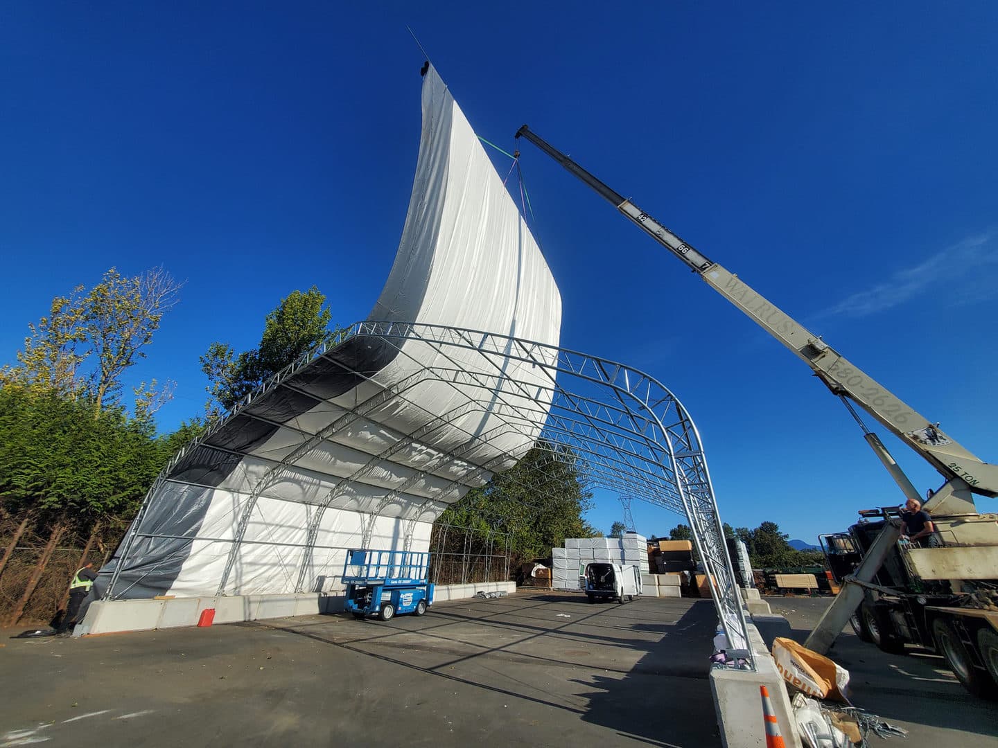 Fabric cover being lifted over a structural frame on a project site.